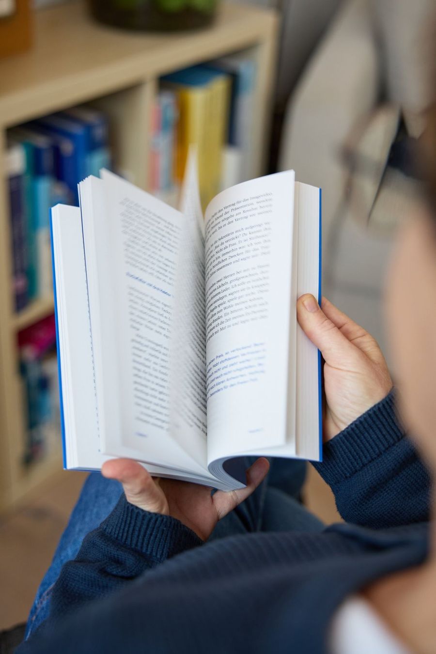 Barbara Schreiber hält ein aufgeschlagenes Buch vor einem Bücherregal
